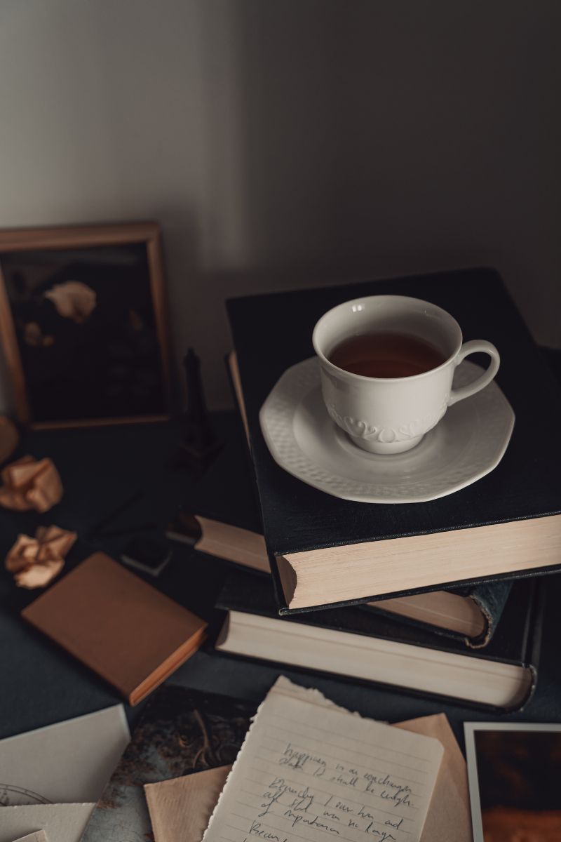 Dark, academia image of tea on books
